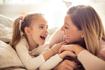 Mother and daughter having conversation in bed.