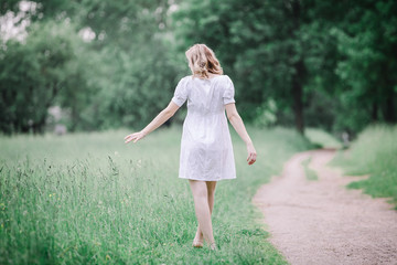 rear view. pregnant woman walking barefoot on grass.