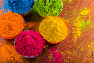 Holi color powder. Organic Gulal colours in bowl for Holi festival, Hindu tradition festive. Blue, pink, magenta, orange, yellow holi dry paints on wood desk background