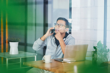 Portrait of Asian businessman calling while working on laptop in office