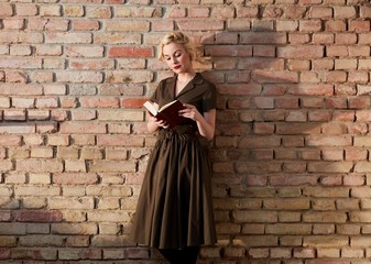 Woman reading book over brick wall