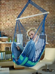 Woman sitting in hanging chair using tablet