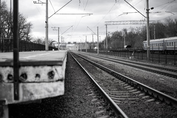 railway rails on which trains go by the station in black and white