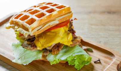 Waffle sandwich with meat, cheese, sauce and vegetables on wooden table background