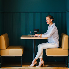 A phenomenal Caucasian woman sitting on a work zone inside a bistro. She is exhibiting amazingly...