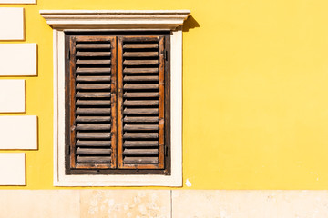 Eine gelbe Mauer mit Fenster und alte Holzfensterläden als Hintergrund