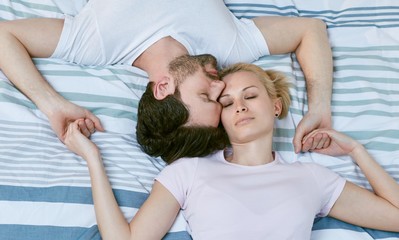 Loving couple lying on bed heads together