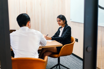 Fototapeta premium A perfect Indian lady sitting close by an assistant inside a gathering room. She is discussing some approach and looking flawless in her office attire.