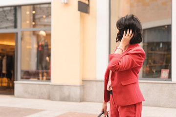 A dark-haired woman in fashionable clothes of the color of the year 2019 living coral standing in the shopping mall. Fashion and Shopping concept.