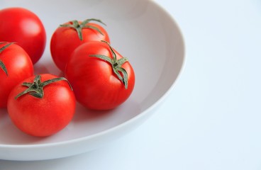 red tomatoes in a white plate on a white background
