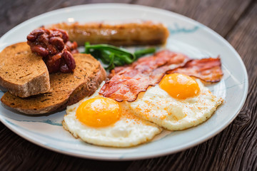 Typial breakfast with eggs, bacon and sausage on plate