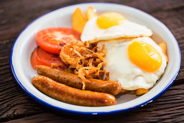 Typial breakfast with eggs, tomato, onion rings and sausage on plate