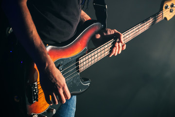 Guitarist plays on of bass guitar - obrazy, fototapety, plakaty