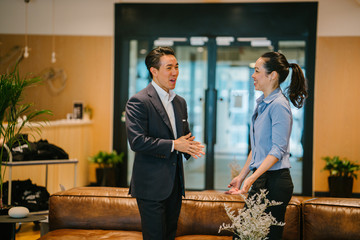 Portrait of two Asian Chinese business people in a corporate attire having a casual discussion in...