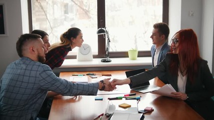 Business concept. A conference. Wirking people sits by table and greeting each other with a handshake