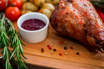 Close up roasted turkey filet with spices, vegetables and jam on wooden board
