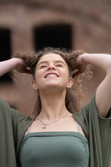 Cheerful young woman touching her hair and looking up.  Roman forum in the background.