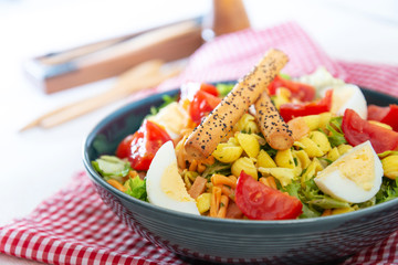 Salad of pasta, egg, smoked salmon tartare, salad and tomato, with a citrus vinaigrette sauce.