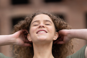 Cheerful young woman touching her hair and looking up.  Roman forum in the background.