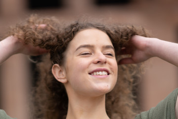 Cheerful young woman touching her hair and looking up.  Roman forum in the background.