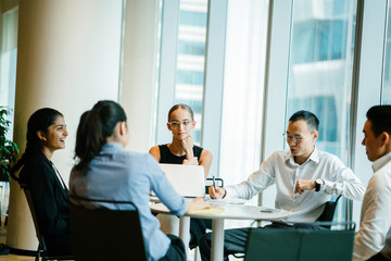A group of professionals discussing a project inside a conference room. They are meeting up to finish a certain job in corporate attire and elegant dresses. 