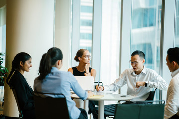 A group of professionals discussing a project inside a conference room. They are meeting up to...