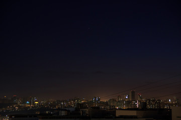 City skyline at night. Amazing panoramic view of modern city.Construction site with cranes on new residential areas.Stars on dark blue sky