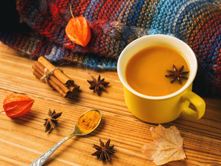 turmeric tea with milk and spices on wooden background