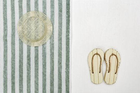 Concept of beach holiday. Beach flip-flops, straw hat. Beach towel striped pattern. Summer flat lay. Copy space.