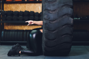Naklejka na ściany i meble Fit female athlete working out with a huge tire, turning and carry in the gym. woman exercising with big tire.
