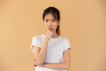 Portrait of obused asian woman wearing basic t-shirt posing at camera with angry look