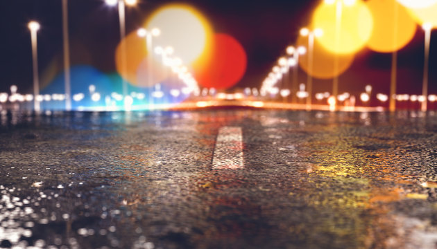 Fondo de asfalto y carretera en la ciudad de noche.Luces de farolas y edificios y charcos en el suelo h&uacute;medo despu&eacute;s de la lluvia