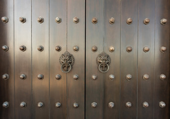 metal Oriental lion handle on teak wood door. antique oriental door knocker.