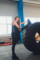 Fototapeta na wymiar Fit female athlete working out with a huge tire, turning and carry in the gym. woman exercising with big tire.