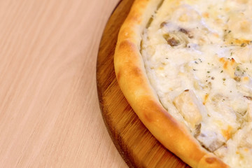 Half of slicing pizza with mushrooms champignons and cheese on wooden board on the table. Close-up side view