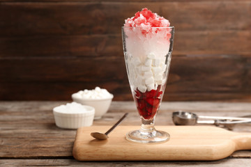 Glass of snow ice cream with raspberry and  marshmallow on table against wooden background. Space...