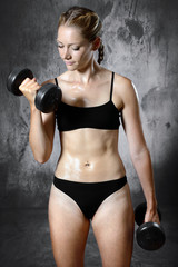 Fototapeta premium Muscular, fit and sporty woman exercising with dumbbells and weights in the studio