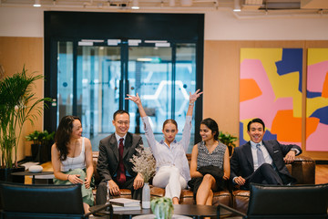 Portrait of a happy business group sitting on a couch in their office. All are professionally dressed and making a wacky pose.