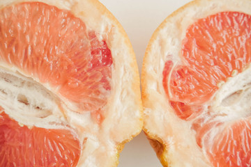 Halved grapefruit close up. Citrus fruit. Healthy eating. Pink color wallpaper. White background