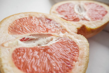Halved grapefruit close up. Citrus fruit. Healthy eating. Pink color wallpaper. White background