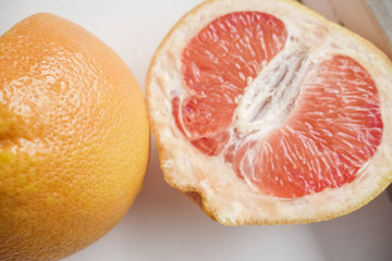 Halved grapefruit close up. Citrus fruit. Healthy eating. Pink color wallpaper. White background