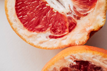 Halved grapefruit close up. Citrus fruit. Healthy eating. Pink color wallpaper. White background