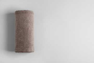 Fresh fluffy rolled towel on grey background, top view with space for text