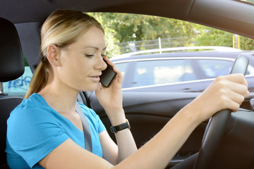 Woman as a driver is unfocused and on the phone during the car ride