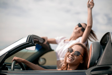 close up.two happy young women in a convertible car
