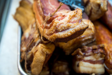 Big pile of whole bacon. Big smoked bacon. Pieces of smoked bacon large in the store