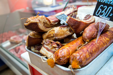 Big pile of whole bacon. Great smoked bacon. Smoked sausage. Salted lard. Inscription in Russian: smoked bacon, Krakow sausage