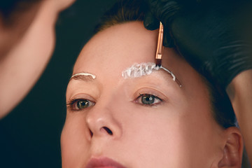 Obraz premium Master makes eyebrows. Eyebrow lamination. The girl makes eyebrows in the salon. Beautiful eyebrow shape. Professional eyebrow lamination.