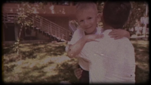 Family video archive. Retro camera 8 mm. Old film.young father playing with his son near the house. Embrace. Family games. Holiday, holidays. Family together