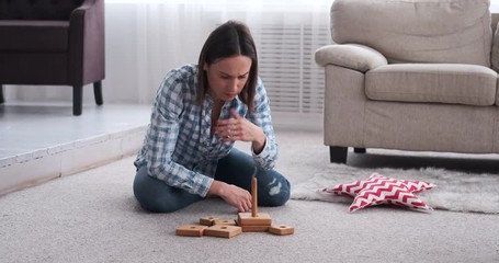 Young woman stacking wooden toy blocks at home